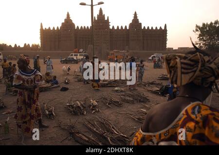 Frauen arrangieren Brennholz vor dem größten Lehmziegel- oder lehmziegelgebäude der Welt, der Großen Moschee von Djenné in Mali, Westafrika. Stockfoto