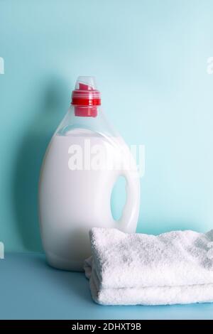 Waschmittel in der Flasche mit Flüssigkeit und Handtücher auf blauem Hintergrund. Wasch- oder Bleaching-Konzept Stockfoto
