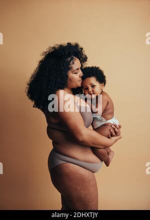 Afroamerikanische Frau und Baby. Mutter hält ihr niedliches Baby in den Armen. Stockfoto