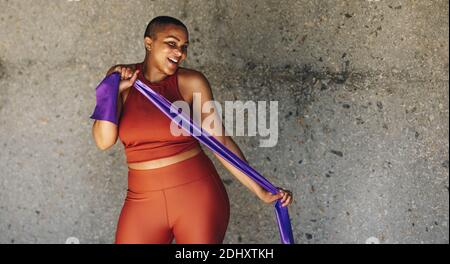 Plus Size Frau Workout mit Widerstand Band. Glückliche Frau in Fitness-Kleidung trainieren im Freien. Stockfoto