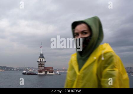 Istanbul, TUR. Dezember 2020. Eine Frau mit Schutzmaske geht vor dem historischen Mädchenturm im Hintergrund während einer Ausgangssperre am Wochenende, die zur Verhinderung der Ausbreitung der Coronavirus-Krankheit (COVID-19) in Istanbul, Türkei, verhängt wurde. Quelle: Jason Dean/ZUMA Wire/Alamy Live News Stockfoto