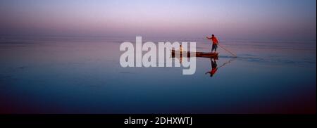 Zwei Peopel auf einem alten hölzernen Boot beobachten den Sonnenaufgang Manchhar See in Pakistan. Stockfoto