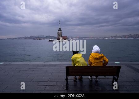 Istanbul, TUR. Dezember 2020. Zwei Frauen sitzen auf der Bank vor dem historischen Maidenturm im Hintergrund während einer Ausgangssperre am Wochenende, die zur Verhinderung der Ausbreitung der Coronavirus-Krankheit (COVID-19) in Istanbul, Türkei, verhängt wurde. Quelle: Jason Dean/ZUMA Wire/Alamy Live News Stockfoto