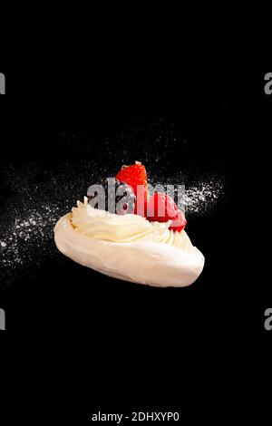 Köstliche Mini Pavlova Meringue Kuchen mit frischen Früchten auf schwarzem Hintergrund dekoriert. Stockfoto