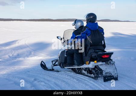 Schneemobil-Touristik-Tour auf dem zugefrorenen See von Inari, in Lappland, Finnland Stockfoto