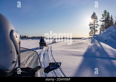 Schneemobil-Touristik-Tour auf dem zugefrorenen See von Inari, in Lappland, Finnland Stockfoto