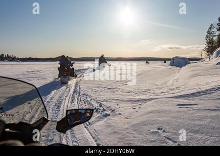 Schneemobil-Touristik-Tour auf dem zugefrorenen See von Inari, in Lappland, Finnland Stockfoto