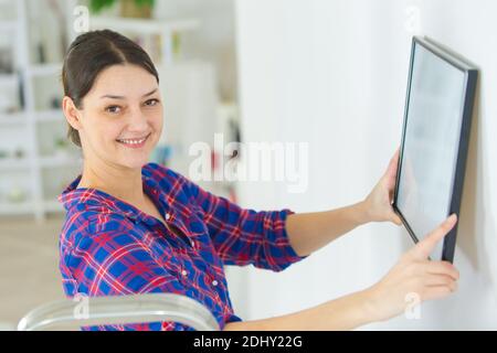 Frau hängt ein Bild an die Wand Stockfoto