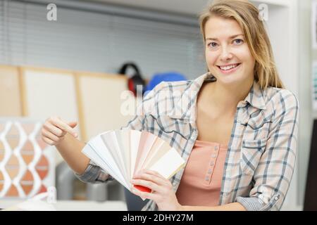 Glückliche Frau untersucht Farbmuster im Büro Stockfoto