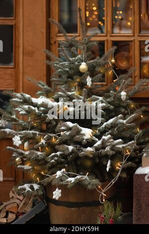 Weihnachtsbaum mit einem Kranz mit Lichter, Kugeln und Schneeflocken unter dem Fenster auf der Straße eingerichtet. Dekoration für das Haus für den Urlaub mit einem Stockfoto