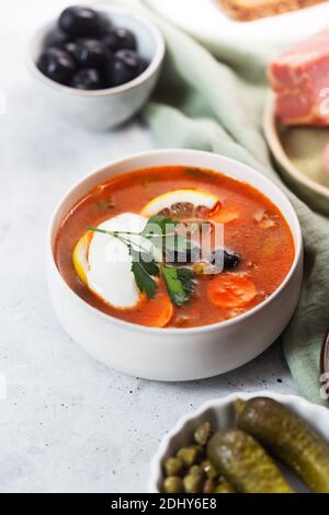 Solyanka, russische Suppe mit Wurst, Oliven, eingelegte Gurken und Kapern Stockfoto