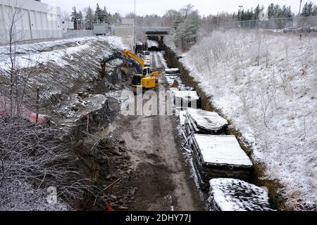 Unter Ballastmatten und einem Bagger, der die Gleise für die Modernisierung/Erweiterung der Trillium-Linie in Carling Station, Ottawa, Ontario, Kanada, erweitert. Stockfoto