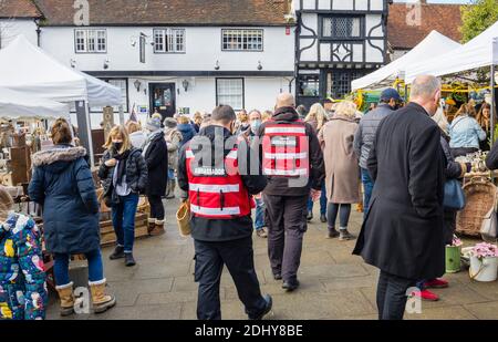 COVID-Botschafter unterstützen bei sozialer Distanzierung und tragen Gesichtsbezüge auf der Country Brocante Winter Fair, Market Square, Midhurst, West Sussex Stockfoto