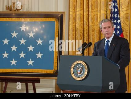 Washington, D.C., 4. April 2005 -- US-Präsident George W. Bush macht Bemerkungen, bevor er am 4. April 2005 die höchste Auszeichnung der Nation für Tapferkeit, die Ehrenmedaille, an Sergeant First Class Paul Ray Smith, United States Army, posthum im East Room des Weißen Hauses in Washington, D.C., verliehen hat. Sergeant Smith wurde am 4. April 2003 getötet, während er über hundert Truppen unter seinem Kommando in der Nähe des Flughafens Bagdad schützte. Smith ist der erste Soldat der Operation Iraqi Freedom, der mit der Ehrenmedaille ausgezeichnet wurde. Die Flagge auf der Staffelei links ist die erste, die seit mir vergeben wird Stockfoto