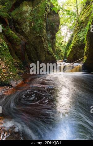 Roter Wasserlauf in schottland mit Wasserfall Stockfoto