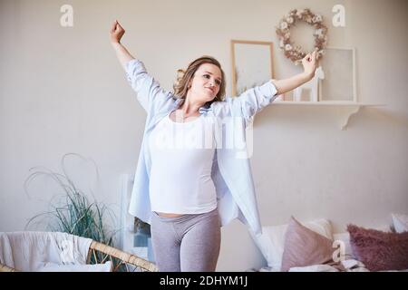Schöne junge schwangere Frau tut Morgen Übungen zu Hause. Glückliche und gesunde Schwangerschaft, Konzept von Frieden und Glück. Stockfoto