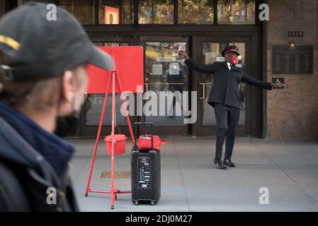 Manhattan, New York. Dezember 11, 2020. Ein Mann geht vor einem Glockenringer der Heilsarmee, der vor Macy's Haupteingang am Herald Square spielt. Stockfoto