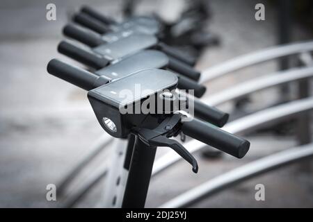 Aufgereiht öffentlichen Elektro-Scooter zur Miete in der Stadt. Elektroroller Transport, schnelle Fahrt. Lenkrad des Elektrorollers. Stockfoto