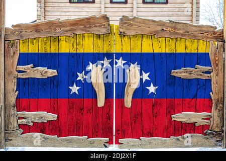 Nahaufnahme der Nationalflagge Venezuelas auf einem Holztor am Eingang zum geschlossenen Territorium. Das Konzept der Lagerung von Waren, Eintritt in einen Abschluss Stockfoto