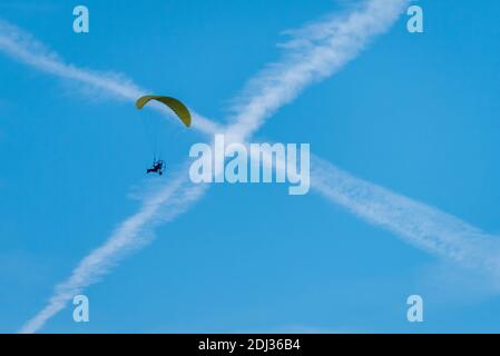 X markiert die Stelle, an der ein motorbetriebener Gleitschirm über einem blauen Himmel über Clermont, Florida, die Durchquerung von Kontrageln überquert. (USA) Stockfoto