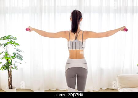 Junge Frau in Sportbekleidung macht Fitness-Stretching-Übungen mit Hantel Zu Hause Stockfoto