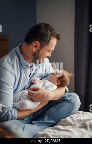 Vatertag. Mittelalter kaukasischen Vater mit schlafen neugeborenen Mädchen. Eltern halten Kind Tochter Sohn auf Armen. Authentische Lifestyle Elternschaft Mutter Stockfoto