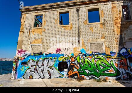 Graffiti an den Wänden eines verlassenen Lagerhauses am Ufer des Tejo in Almada, Portugal Stockfoto