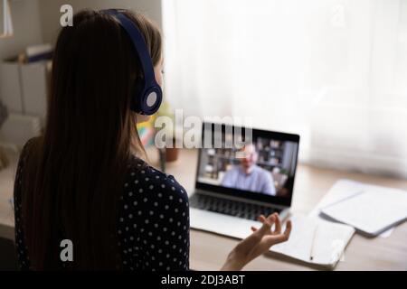 Rückansicht Frau trägt Kopfhörer mit Laptop, macht Videoanruf Stockfoto