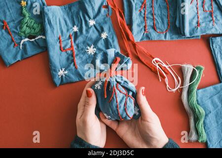 Stoffbeutel für Weihnachtsgeschenke und handgefertigte Zahlen mit Dekorationen auf dem Tisch. Handgemachtes Adventskalender für Weihnachten Stockfoto