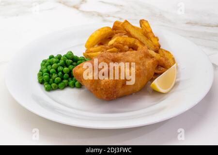 Fisch und Chips mit Erbsen und Zitrone auf einem weißen Teller, ein typisches traditionelles Gericht der britischen Küche mit tiefgebratenen Kabeljau Stockfoto