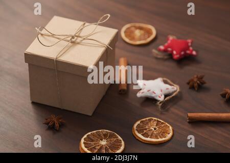 Weihnachts-Geschenkbox aus umweltfreundlichem Papier mit Naturgarn auf Holztisch mit natürlichen Dekorationen verpackt, flacher Fokus