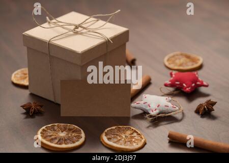Weihnachts-Geschenkbox aus umweltfreundlichem Papier mit Naturgarn auf Holztisch mit natürlichen Dekorationen und Grußkarte verpackt, flacher Fokus
