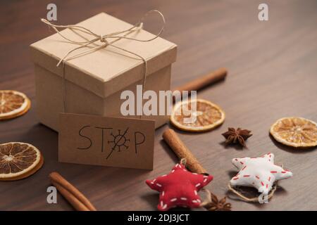 Weihnachts-Geschenkbox aus umweltfreundlichem Papier mit Naturgarn auf Holztisch mit natürlichen Dekorationen und Stoppkarte verpackt, flacher Fokus