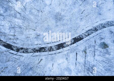 Luftaufnahme einer Straße in einem verschneiten Wald in Winter Stockfoto