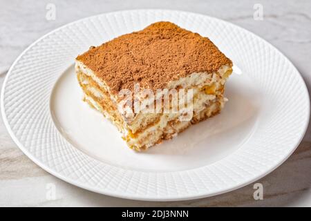 Klassisches italienisches Dessert Tiramisu von Marienkäfer oder savoiardi eingeweicht Espresso und Mascarpone gemischt mit geschlagenem Eiweiß serviert Eine weiße Platte mit Stockfoto