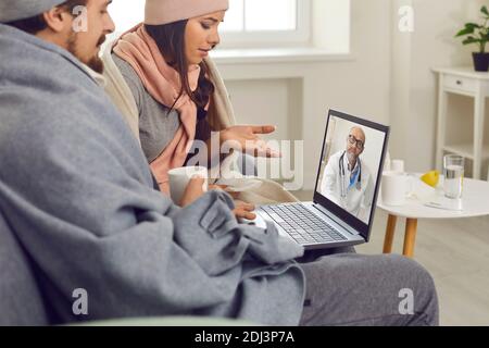 Das kranke Paar hat eine Videokonferenz mit seinem Arzt, der zu Hause auf der Couch sitzt. Stockfoto