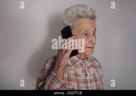 Ältere Person mit dem Smartphone, die einen Anruf macht, angenehme Unterhaltung hat, chattet, gute Nachrichten hört Stockfoto