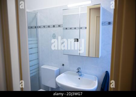 Blick auf das Innere eines Badezimmers von der Eingangstür. Der gelbe Rahmen der Tür ist der Rahmen: In Beweis der Spiegelschrank über dem Waschbecken, o Stockfoto