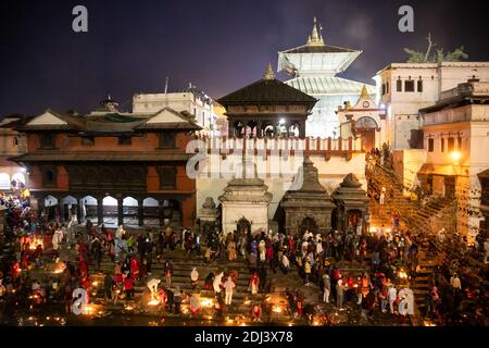 Nepalesische hinduistische Anhänger zünden Öllampen an, um an verstorbene Familienmitglieder während des Bala Chaturdashi-Festivals im Pashupatinath-Tempel zu erinnern.nepalesische hinduistische Anhänger feiern das Festival, indem sie Öllampen anzünden und sieben Arten von Körnern, die als "Sat biu" bekannt sind, entlang einer Route am Tempel zerstreuen, um die Verstorbenen zu ehren. Stockfoto