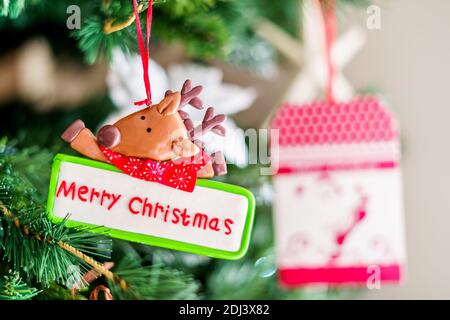 Lustige Elche mit rotem Schal mit fröhlichem Weihnachtsteller, Weihnachtsschmuck. Platz auf der rechten Seite kopieren Stockfoto