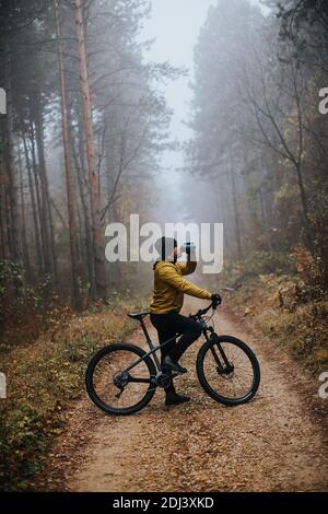 Schöner junger Mann, der beim Radfahren durch den Herbst eine Bremse zieht Wald Stockfoto