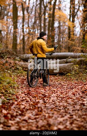 Schöner junger Mann, der beim Radfahren durch den Herbst eine Bremse zieht Wald Stockfoto