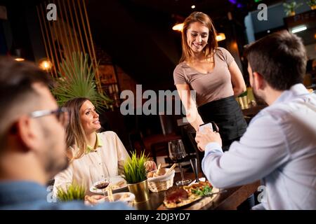 Junger Mann, der kontaktlos mit dem Mobiltelefon im Restaurant bezahlt Nach dem Abendessen Stockfoto