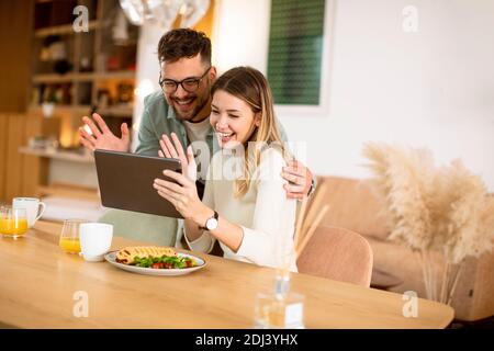 Schönes junges Paar mit digitalen Tablet und mit Frühstück in Die Küche Stockfoto