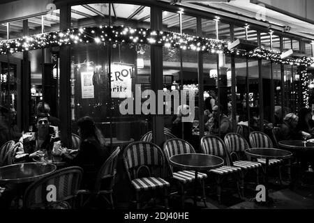 PARIS, FRANKREICH - 2. DEZEMBER 2018: Pariser und Touristen trinken abends im Café Panis (bereits zu Weihnachten dekoriert) in der Nähe von Notre-Dame Stockfoto