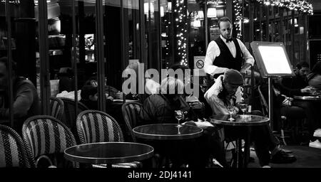 PARIS, FRANKREICH - 2. DEZEMBER 2018: Pariser und Touristen trinken abends im Café Panis (bereits zu Weihnachten dekoriert) in der Nähe von Notre-Dame Stockfoto