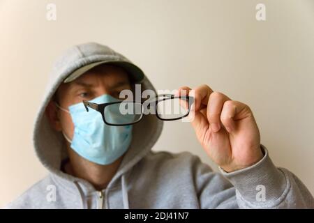 Der Mann in der Maske schaut auf das Schwarz Brille Stockfoto