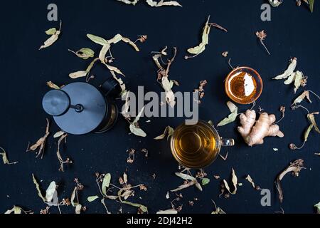 Französische Presse und Kräutertee, auf schwarzem Hintergrund zwischen trockenen Blättern Stockfoto
