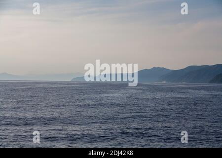 Ein Blick vom Meer auf Berge mit Meeresnebel Stockfoto