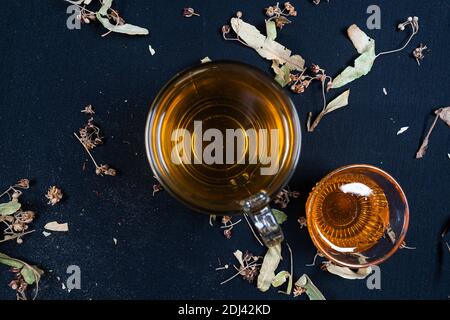 Französische Presse und Kräutertee, auf schwarzem Hintergrund zwischen trockenen Blättern Stockfoto